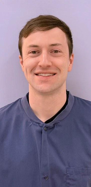Garrett Fillebrown smiling in front of a purple wall.