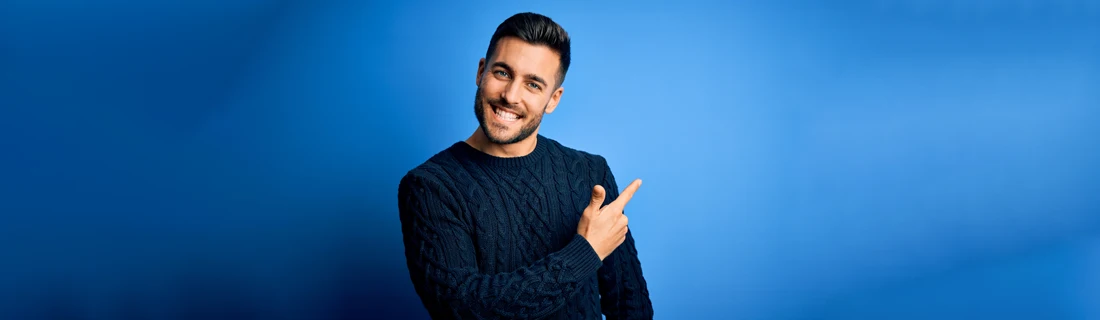 A man smiling in front of a blue wall.