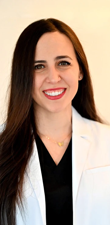 Tamara Basha smiling in front of a yellow wall.